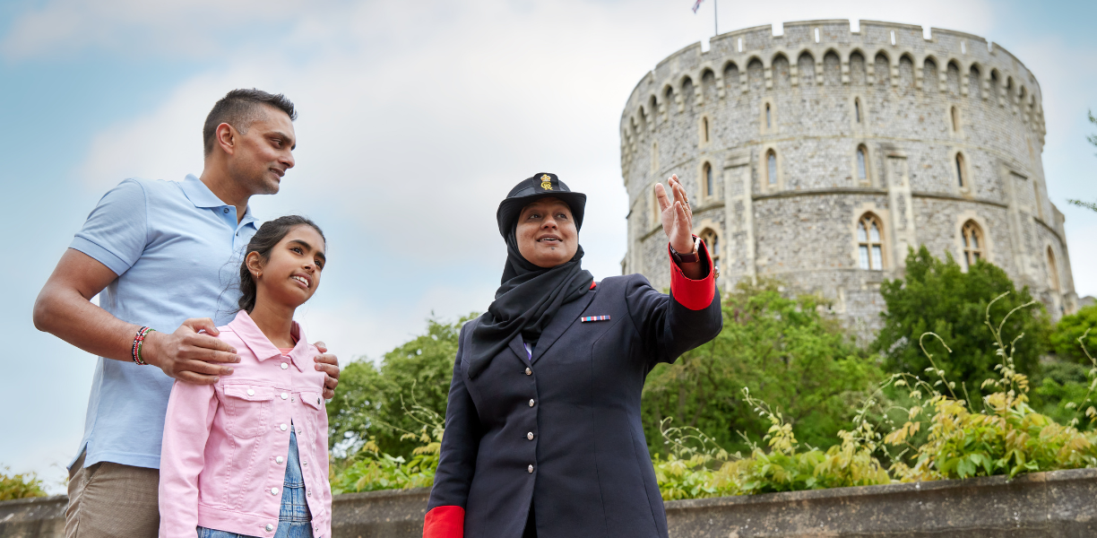 A warden talking to visitors in front of the Round Tower at Windsor Castle